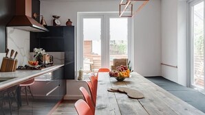 Una cocina moderna con una mesa de madera, sillas rojas y un frutero.