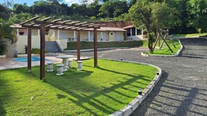 Una villa con piscina, pérgola y césped bien cuidado.