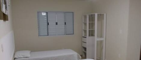 A bedroom with two beds, a ceiling fan, a wardrobe, and a window with blinds.