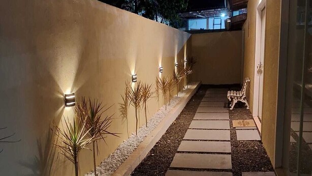Un sendero con iluminación decorativa, pequeñas plantas y un banco.