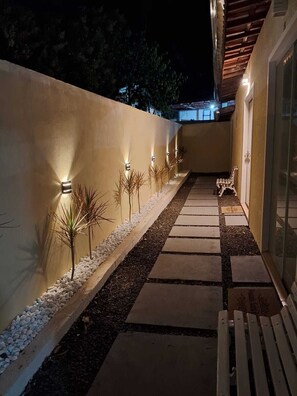Un sendero con iluminación decorativa, pequeñas plantas y un banco.