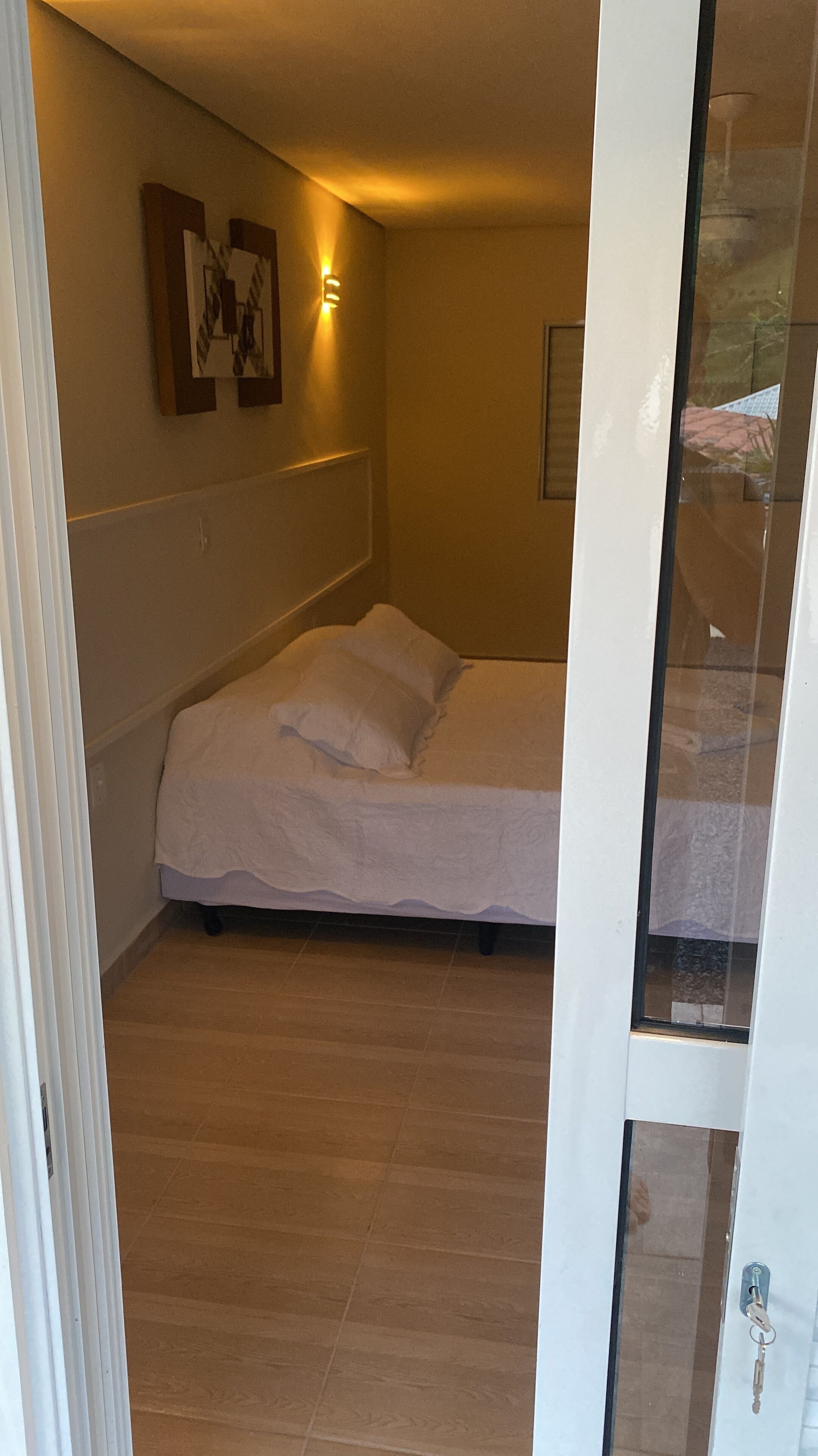A bedroom with a bed, a wall-mounted light, and a door with a key in the lock.