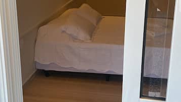 Quarto com cama, luminária na parede e porta com chave na fechadura.
