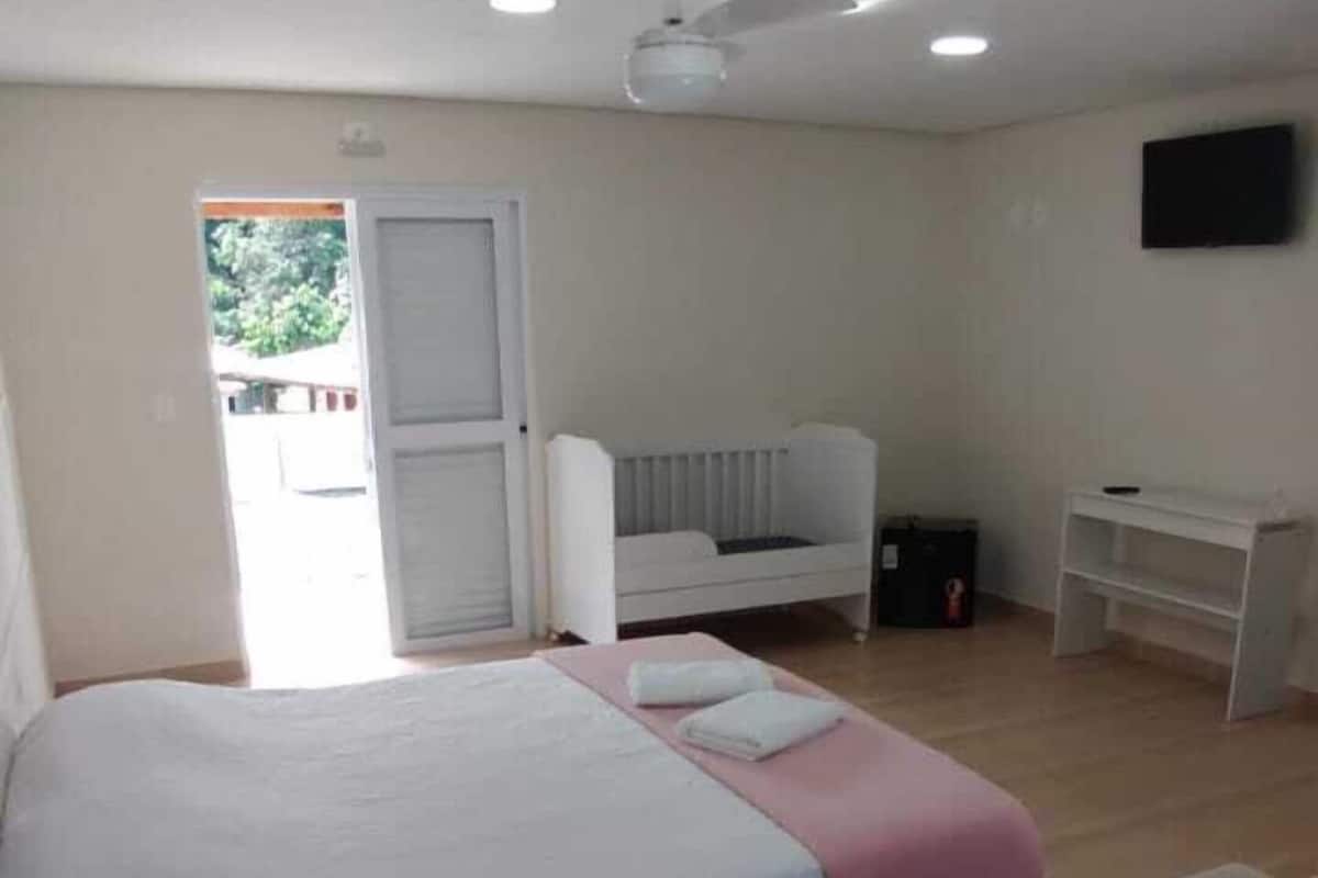 A hotel room with two beds, a desk, a chair, and a television.