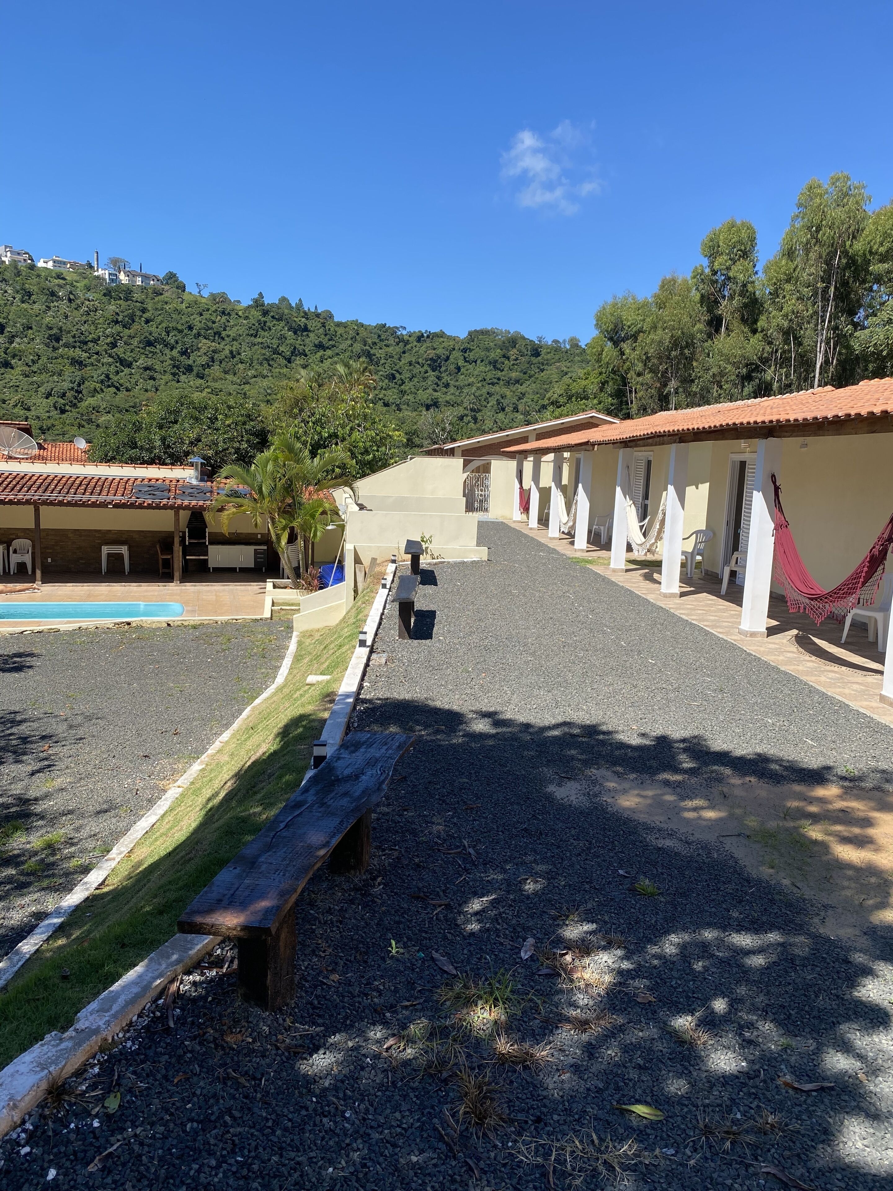 A resort with a pool, outdoor seating, and a view of a forested hill.