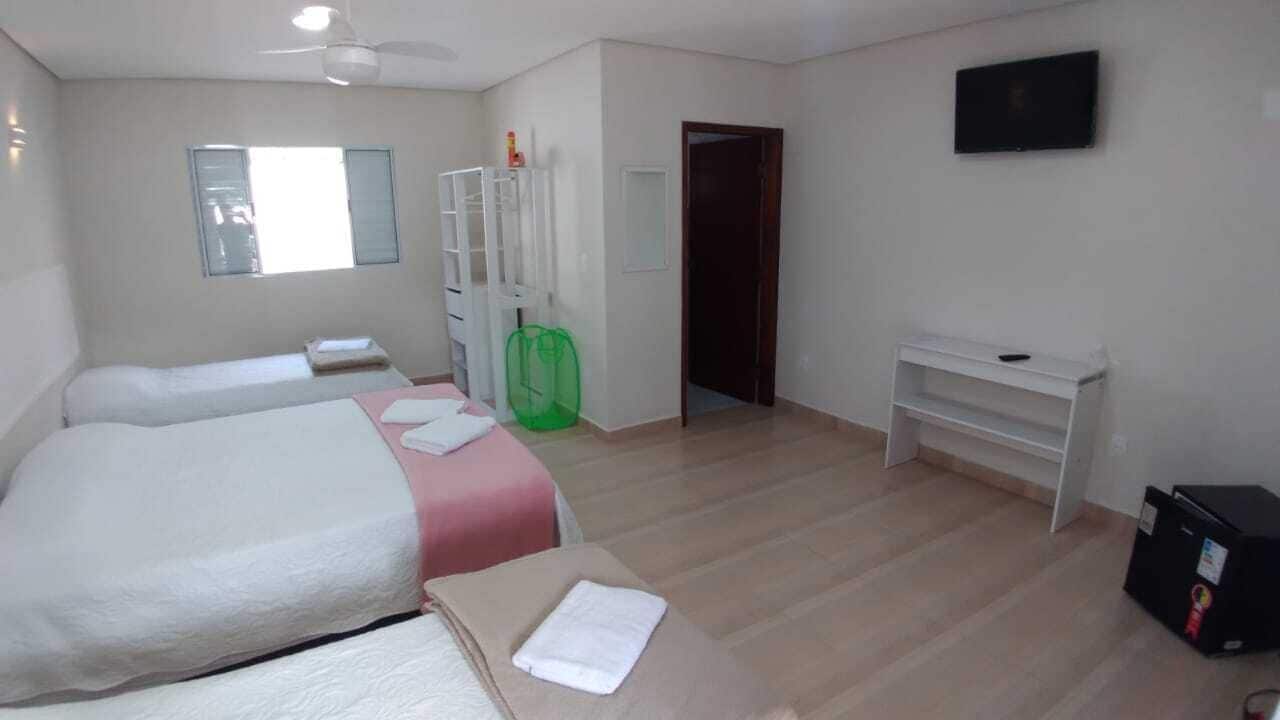 Een hotelkamer met twee bedden, een bureau, een televisie en een kledingkast.