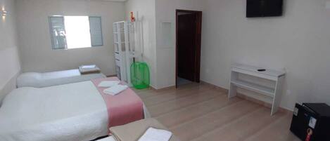 Een hotelkamer met twee bedden, een bureau, een televisie en een kledingkast.