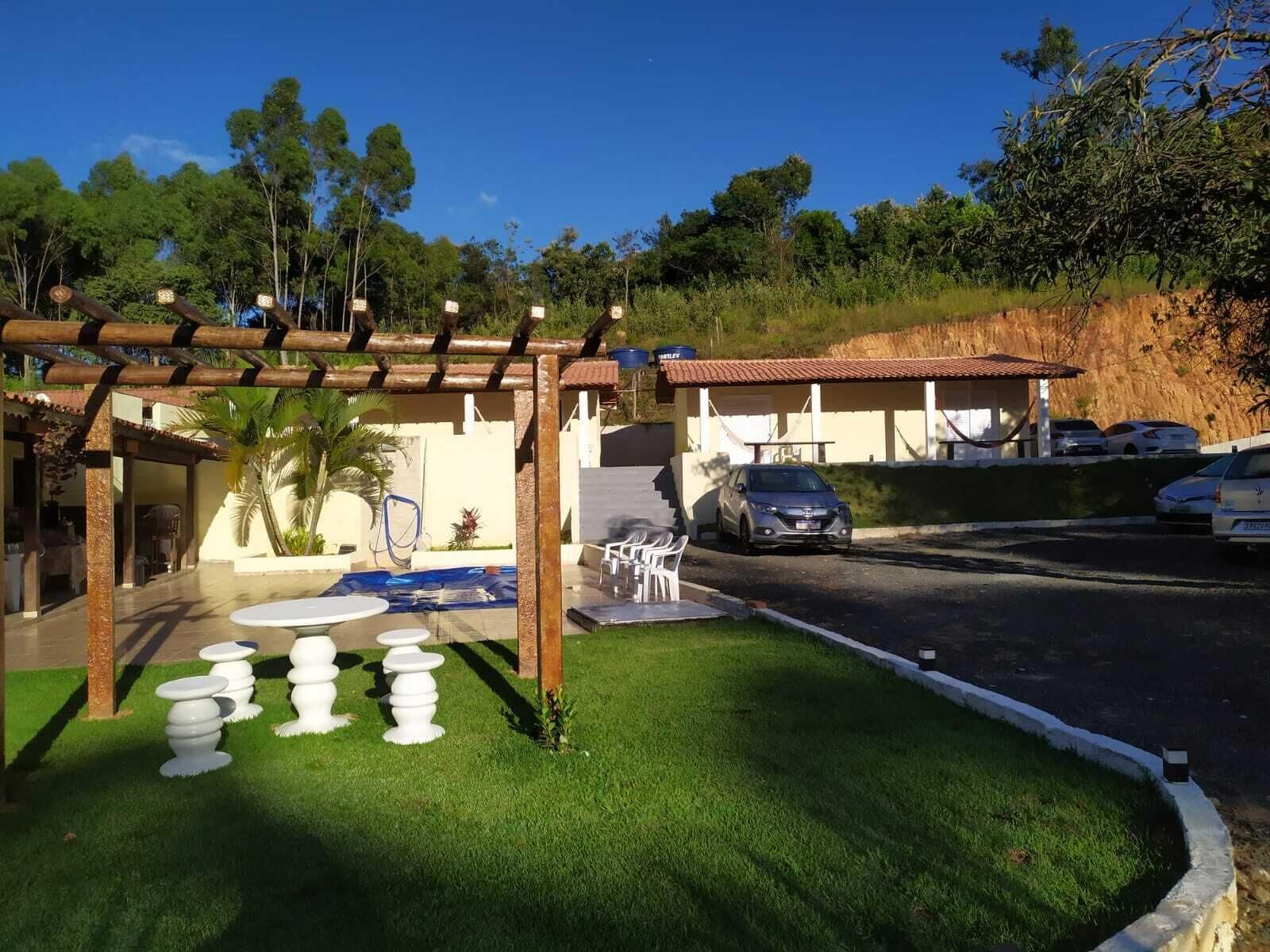 Un espacio al aire libre cubierto con una pérgola, mobiliario exterior y una piscina.