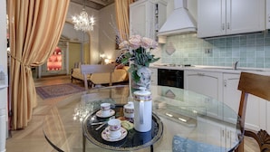 A dining area with a glass table, white cabinets, and a chandelier.