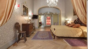 A bedroom with a large bed, a dresser, a chair, and a television on the wall.