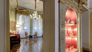 A room with a red sofa, a chandelier, and a display cabinet with decorative items.