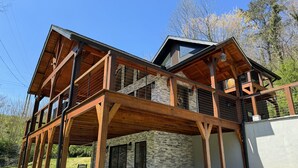 Een houten huis met twee verdiepingen, een stenen fundering, een overdekt terras en een stenen muur.