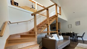 Een modern interieur met een houten trap, een leren bank en een eethoek.