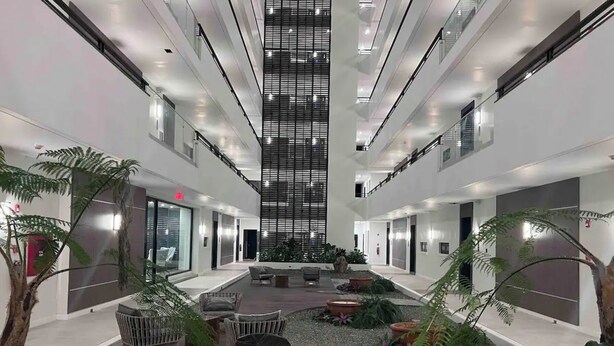 Un moderno atrio interior con un espacio central abierto, zonas de estar y plantas en macetas.