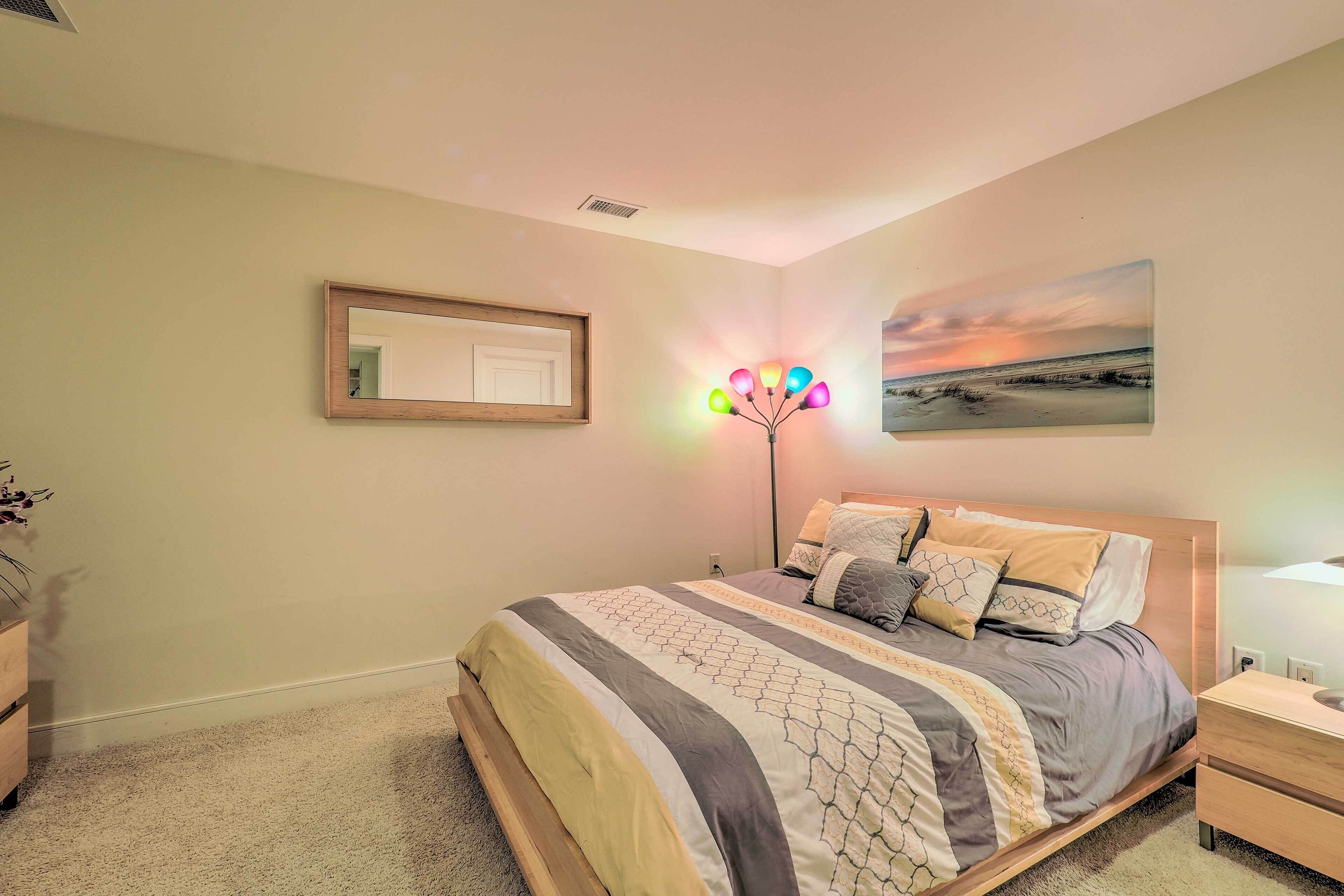 Quarto com cama, mesas de cabeceira, um espelho e luminária na parede.