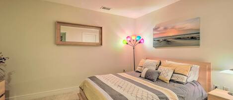 Quarto com cama, mesas de cabeceira, um espelho e luminária na parede.