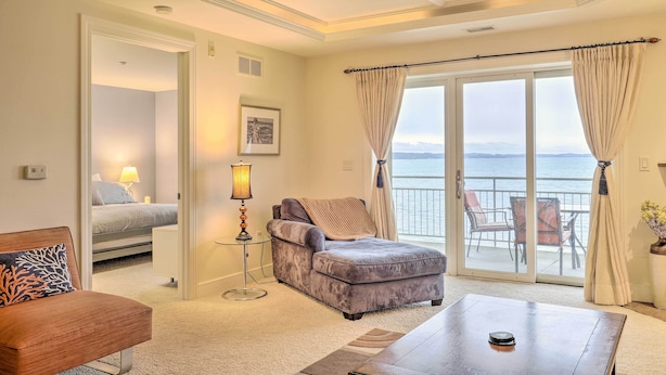 Ein Hotelzimmer mit Bett, Sofa, Esstisch und Meerblick durch große Fenster.