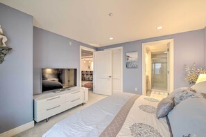 Une chambre à coucher comprenant un lit, une télévision, une armoire et une porte donnant accès à une salle de bain.