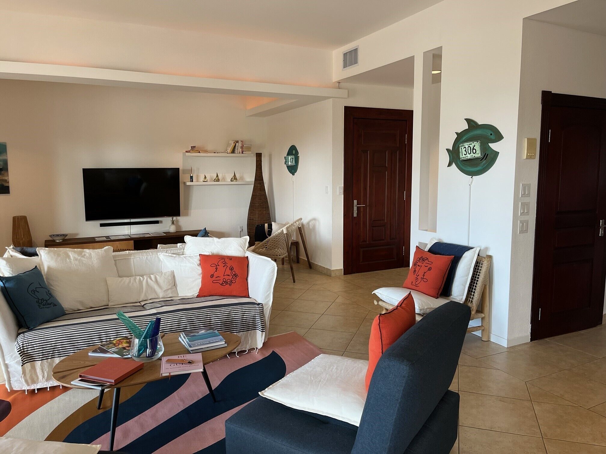 Un salon comprenant un canapé, des fauteuils, une table basse, un téléviseur et des objets de décoration.