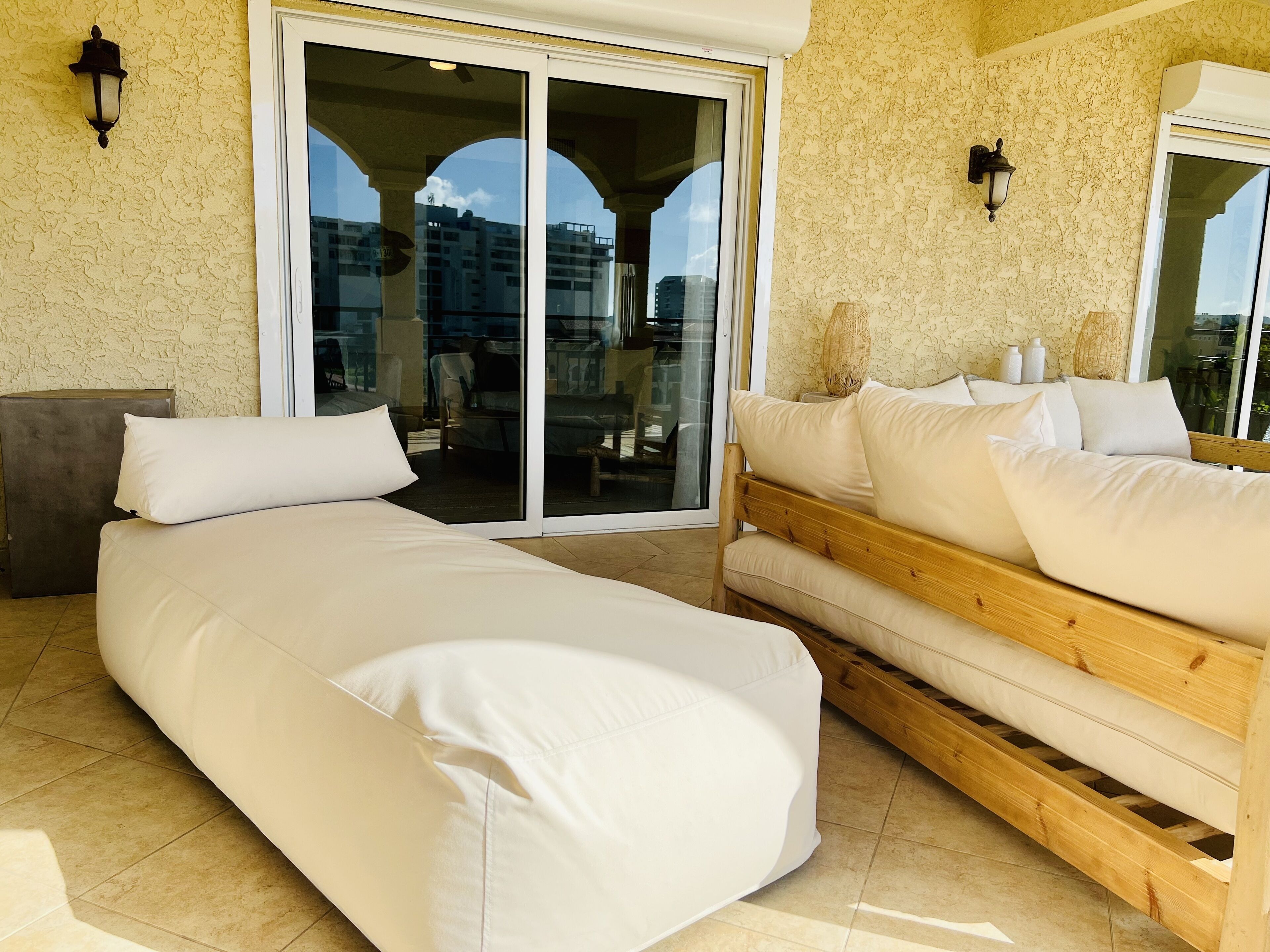Ein Schlafzimmer mit einem großen Bett, einem kleineren Bett und einem Schlafsofa. Eine Glastür führt zu einem Balkon.