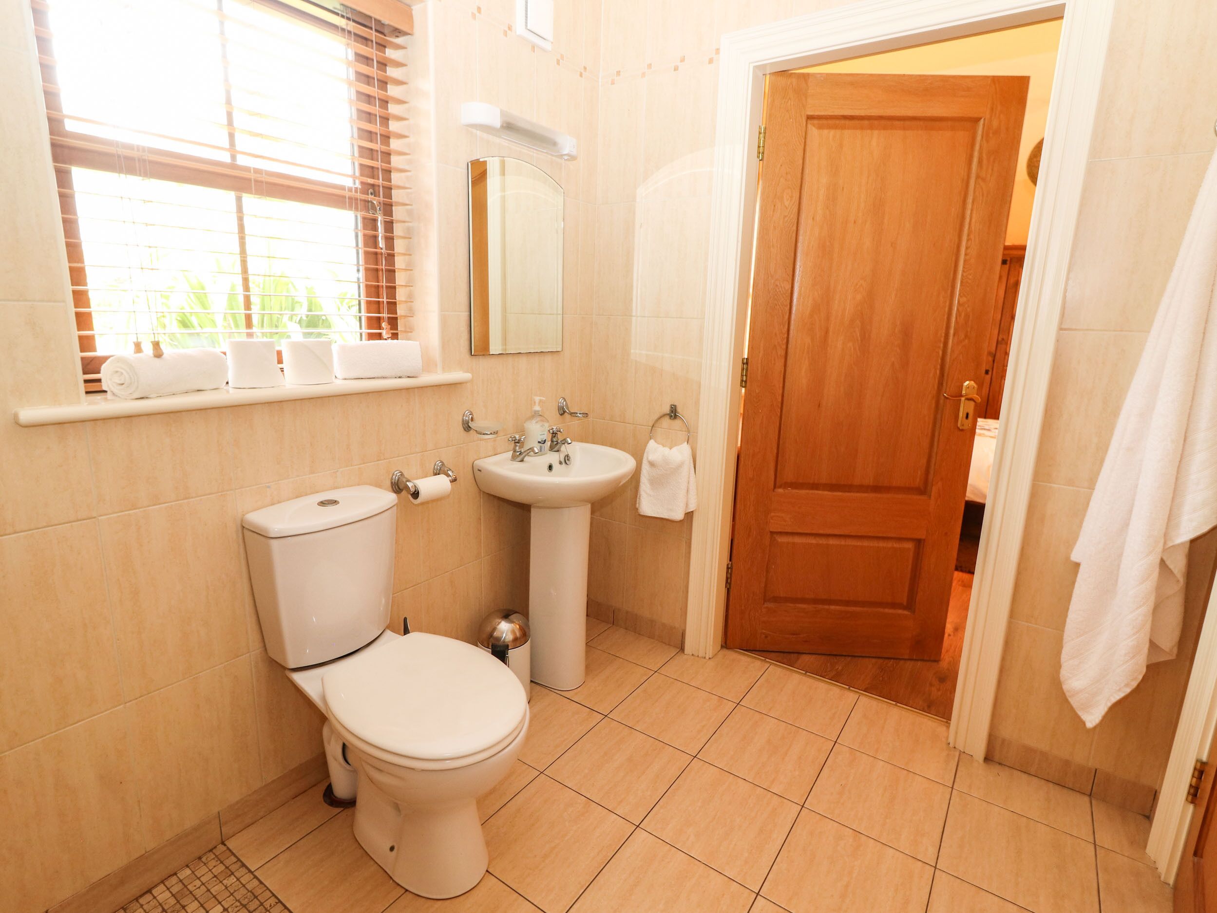 Een badkamer met toilet, wastafel en spiegel.