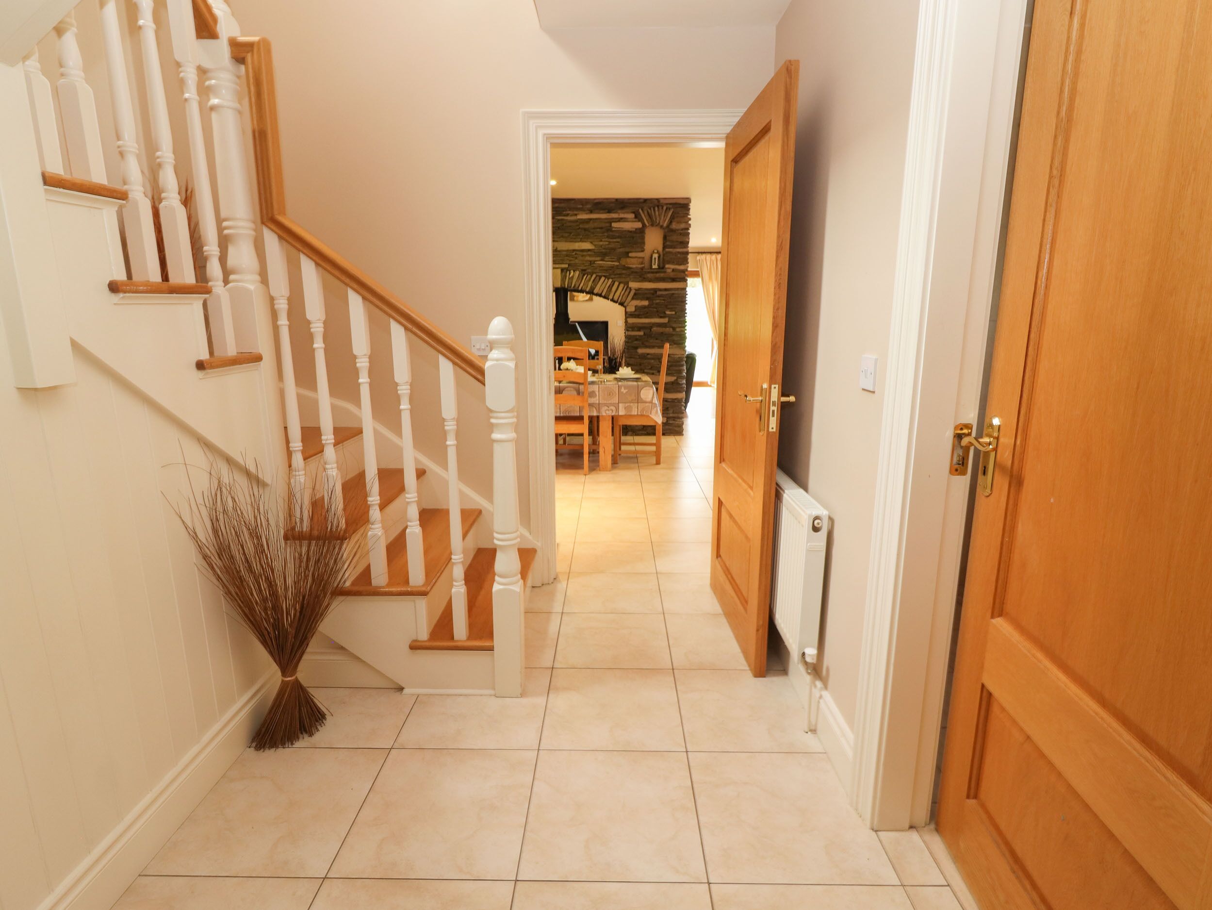 A staircase with white balusters leading to a dining area with a stone wall backdrop.