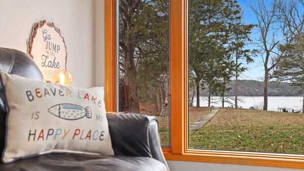 A leather couch with a pillow that reads "Beaver Lake is my happy place" and a sign that says "Go jump in the lake". - Ninnie & Papaw's Paradise Cove on Beaver Lake (Springdale)