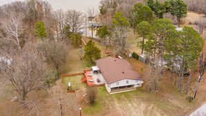 A house with a large backyard, a boat dock, and a lake in the background. - Ninnie & Papaw's Paradise Cove on Beaver Lake (Springdale)