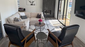 Una sala moderna con un sofá, dos sillones, una mesita de centro y una chimenea.