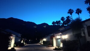 Una calle que lleva a un edificio con una montaña al fondo.