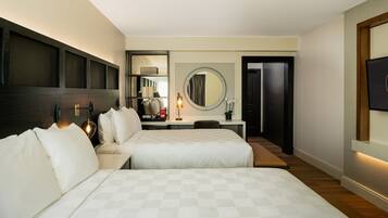 A hotel room with two beds, a desk, a chair, a mirror, and a TV.
