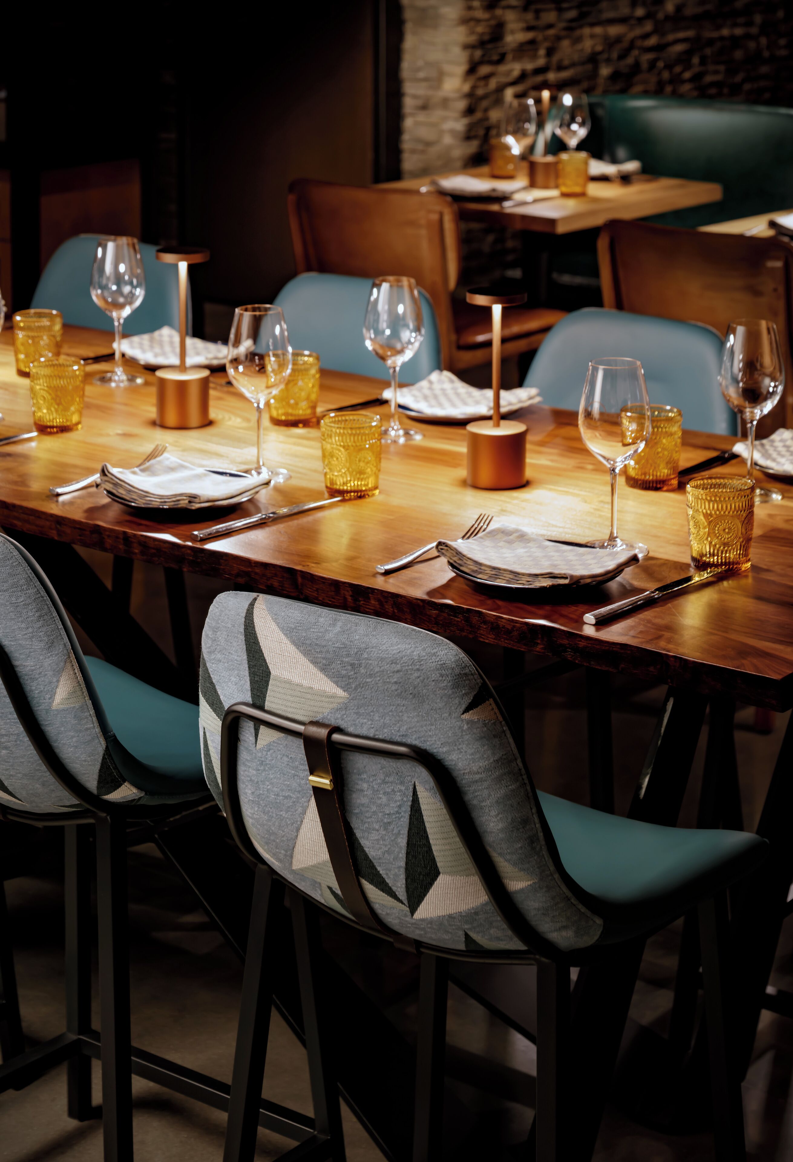 A restaurant setting with a wooden table set for dining, including plates, cutlery, and glasses.