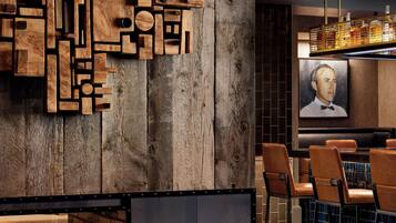 Un espace bar moderne avec un mur en bois, une cheminée et des fauteuils en cuir.