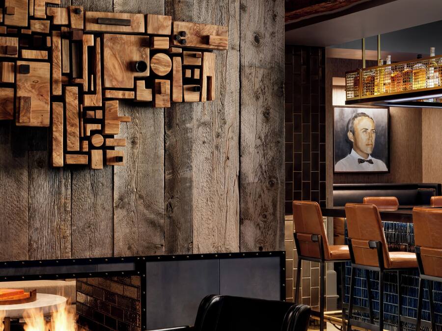 Un espace bar moderne avec un mur en bois, une cheminée et des fauteuils en cuir.