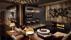 Una sala de estar moderna con chimenea, zona de estar y bar con estantes llenos de botellas.