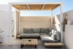 A covered outdoor seating area with a wooden bench, a cushioned sofa, and string lights. - Donna Rosa Holiday Home - Terrazza (Noto)