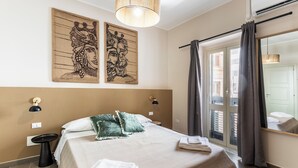 A bedroom with a bed, a bedside table, a wall-mounted lamp, and a window with curtains. - Donna Rosa Holiday Home - Vicolo (Noto)