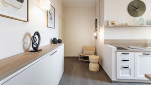 A modern kitchen with white cabinetry, a wooden countertop, a hanging light fixture, and a round wall clock. - Donna Rosa Holiday Home - Vicolo (Noto)