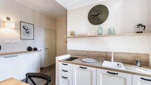 A modern kitchen with white cabinets, a wooden countertop, a sink, and a wall-mounted clock. - Donna Rosa Holiday Home - Vicolo (Noto)