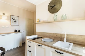 A modern kitchen with a wooden countertop, white cabinets, a built-in sink, and a wall-mounted clock.
