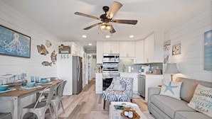 A modern kitchen with white cabinets, a central island, and a ceiling fan.