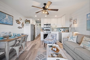 A modern kitchen with white cabinets, a central island, and a ceiling fan.