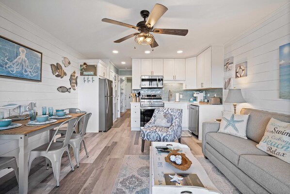 Une cuisine moderne avec des meubles blancs, un îlot central et un ventilateur de plafond.