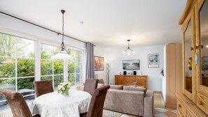 A modern living room with a dining table, chairs, sofa, and wooden cabinet. - Vacation apartment "Vahle 1" up to 4 persons (non-smoking) (Niendorf/Ostsee)