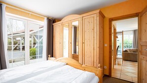 A hotel room with a large bed, wooden wardrobe, and a sliding glass door leading to a balcony. - Vacation apartment "Vahle 1" up to 4 persons (non-smoking) (Niendorf/Ostsee)