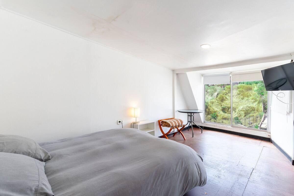 Ein Schlafzimmer mit einem Bett, einem kleinen Tisch, einem Sessel und einem Fernseher.