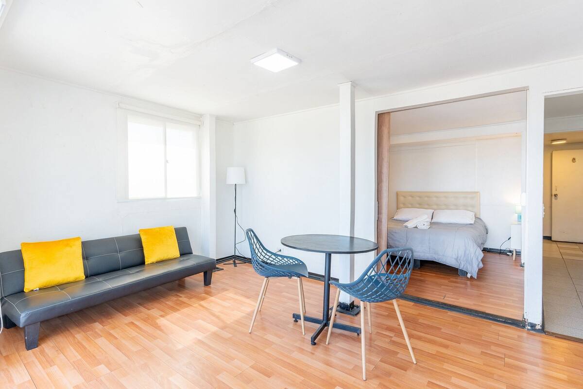Ein modernes Zimmer mit einer Couch, zwei Sesseln, einem kleinen runden Tisch und einem Bett.