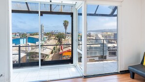 Una habitación con un amplio ventanal corredera que da a un balcón con vistas a la ciudad y al mar.