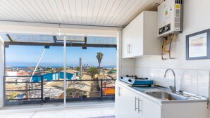 Una cocina con un ventanal grande, un lavamanos y un calentador de agua.
