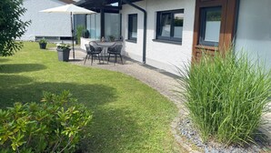 A modern house with a patio, a table with chairs, and potted plants. - Modern, 4-star **** apartment (2 rooms, 80 sqm), between Oberstaufen and Lake Constance (Weiler-Simmerberg)